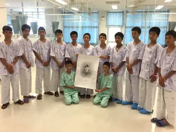 Los niños rescatados de la cueva posan junto a un retrato del buzo fallecido Los niños rescatados de la cueva posan junto a un retrato del buzo fallecido