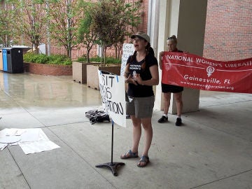Estudiantes sosteniendo carteles y hablando durante una protesta en la la Universidad de Florida