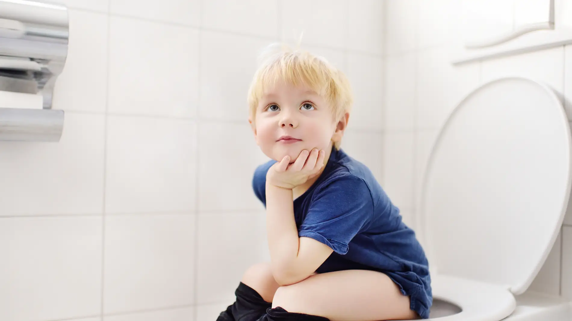 Niño sentado en urinario