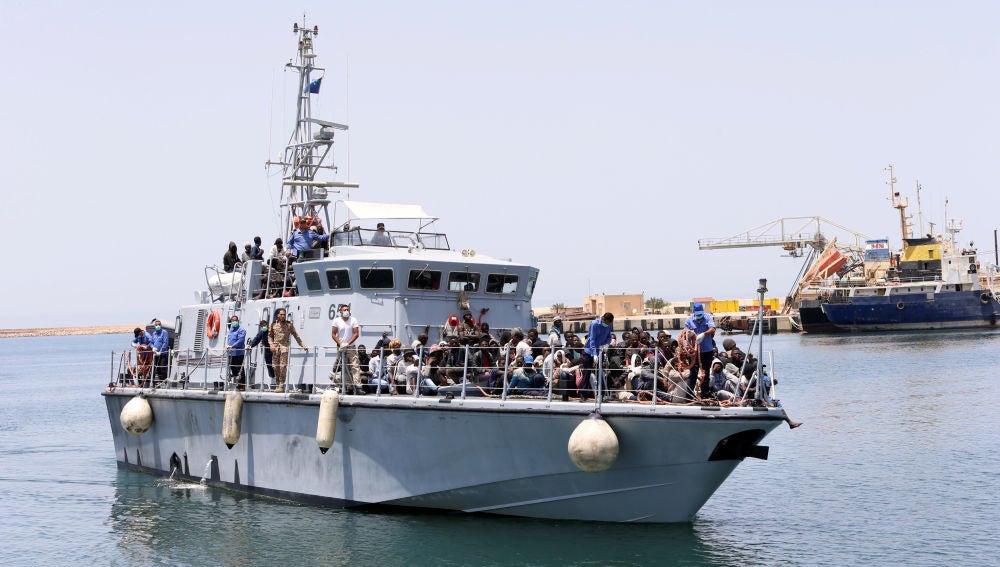 Un barco de la Armada de Libia con inmigrantes a bordo llega a una base