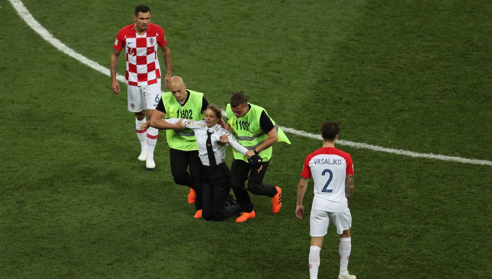 Los miembros de seguridad sacan del campo a una activista en la final del Mundial