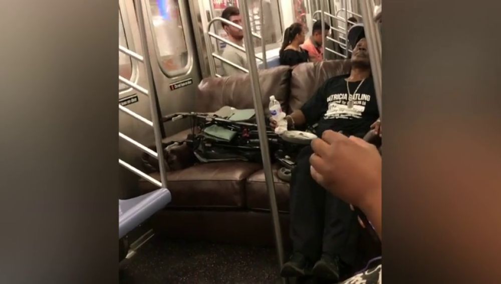 Unos pasajeros utilizan un sofá para sentarse en el vagón del metro