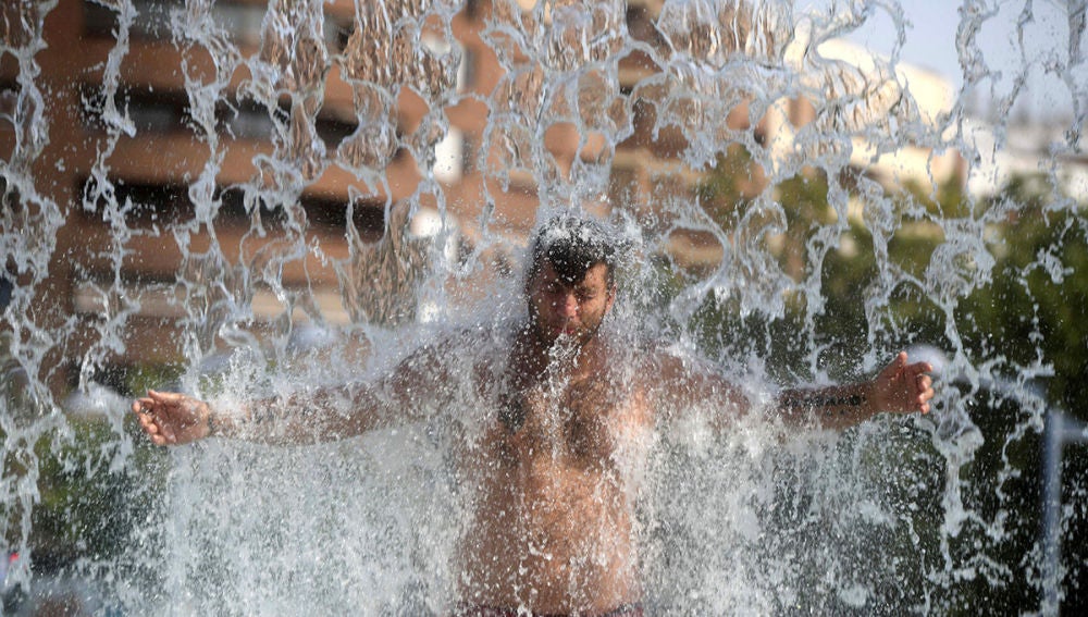 Un hombre se refresca en una fuente de Córdoba durante la ola de calor