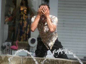 Un hombre intenta refrescarse en una fuente de Córdoba, en una jornada marcada por la ola de calor que afecta a toda la Península
