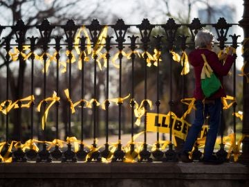 Una mujer coloca lazos amarillos en la verja del Pac de la Ciutadella
