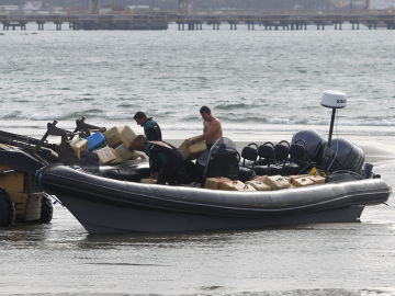 Agentes de la Guardia Civil trasladan los fardos de hachís incautados en una embarcación de tipo neumática en Cádiz