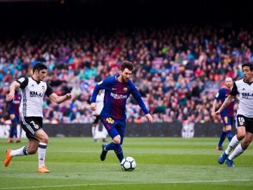 Guedes y Parejo intentan arrebatar el balón a Messi