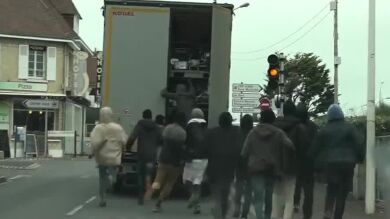 Decenas de inmigrantes tratan de subir a un camión en Calais para poder cruzar a Inglaterra