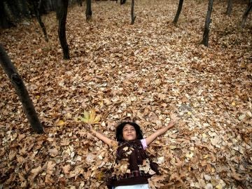 Imagen de archivo de una joven tumbada sobre las hojas caídas del otoño