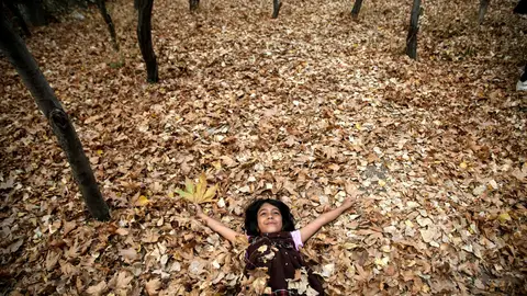Imagen de archivo de una joven tumbada sobre las hojas caídas del otoño Imagen de archivo de una joven tumbada sobre las hojas caídas del otoño