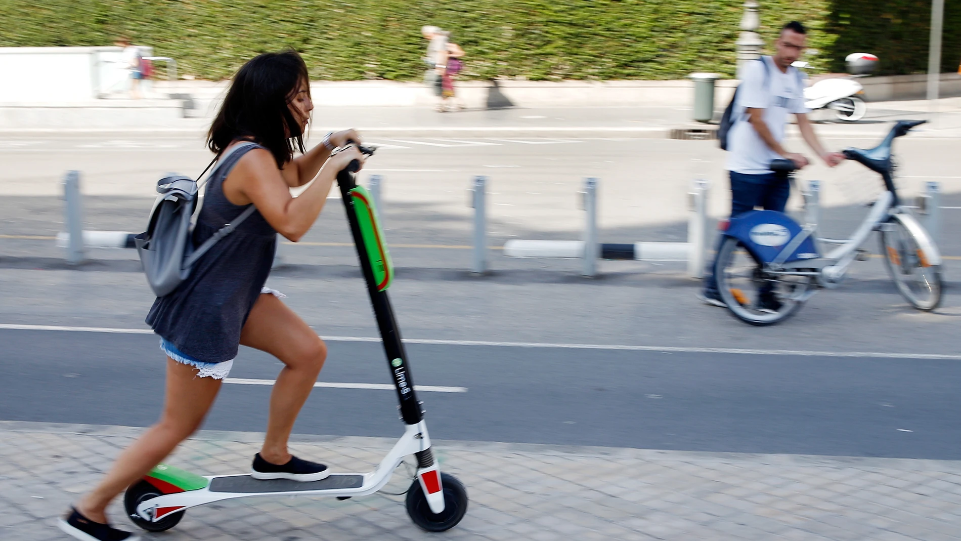 Una joven circulando en un patinete eléctrico Una joven circulando en un patinete eléctrico