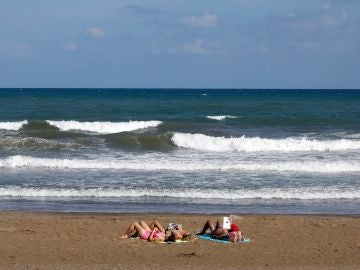 Tres personas toman el sol, el pasado mes de septiembre en la playa de la Malvarrosa de Valencia