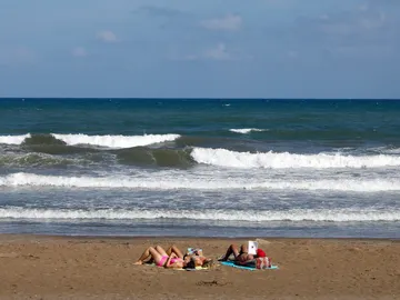Tres personas toman el sol, el pasado mes de septiembre en la playa de la Malvarrosa de Valencia Tres personas toman el sol, el pasado mes de septiembre en la playa de la Malvarrosa de Valencia