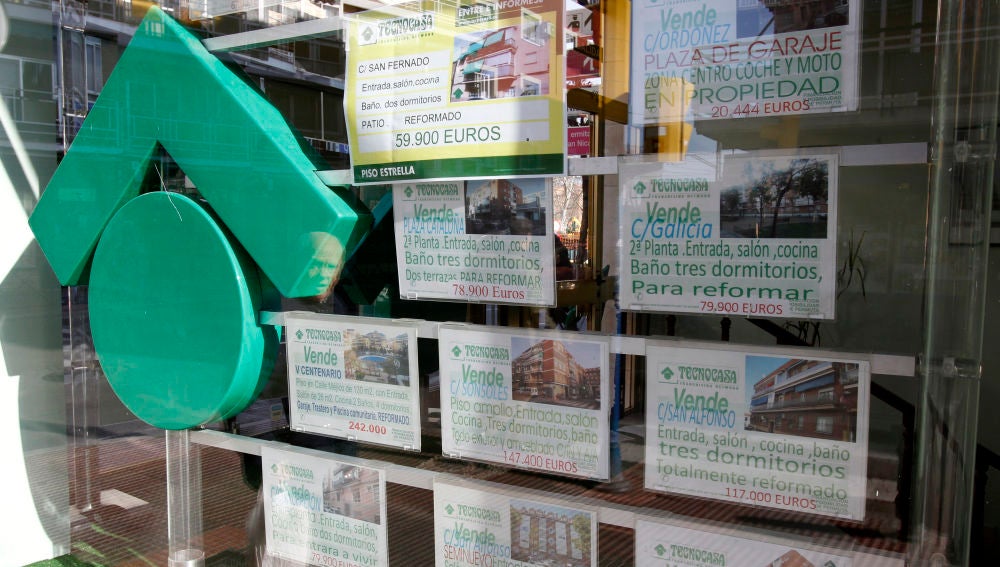 Numerosos carteles de venta de pisos ocupan el escaparate de una entidad inmobiliaria