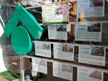 Numerosos carteles de venta de pisos ocupan el escaparate de una entidad inmobiliaria