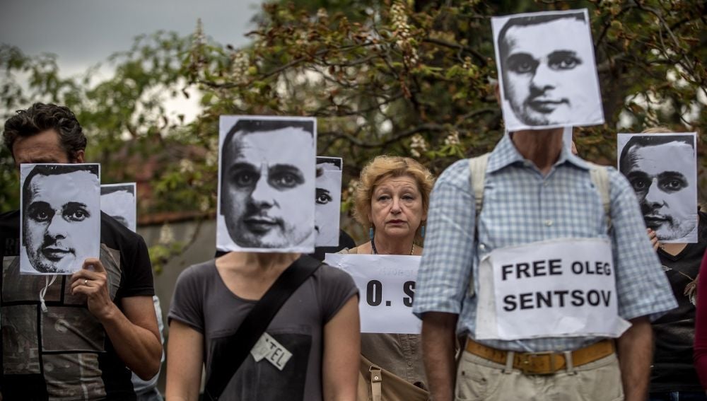 Varias personas sostienen pancartas y máscaras del cineasta ucraniano encarcelado en Rusia, Oleg Sentsov