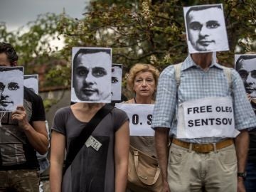 Varias personas sostienen pancartas y máscaras del cineasta ucraniano encarcelado en Rusia, Oleg Sentsov