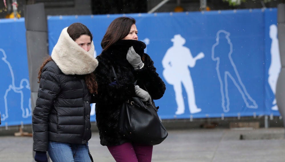 Dos personas se protegen del frío en una céntrica calle de Madrid
