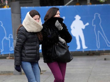 Dos personas se protegen del frío en una céntrica calle de Madrid