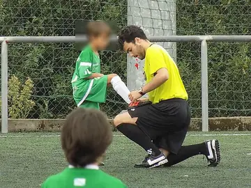 Un árbitro le ata los cordones a un niño Un árbitro le ata los cordones a un niño