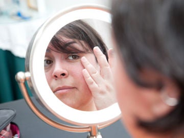 Mujer se mira la cara frente al espejo