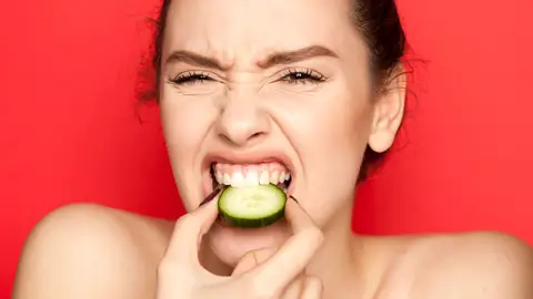 Chica mordiendo rodaja de pepino Chica mordiendo rodaja de pepino