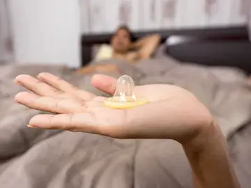 Una mujer con un preservativo en la mano Una mujer con un preservativo en la mano