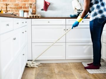Una mujer friega el suelo de la cocina de su casa