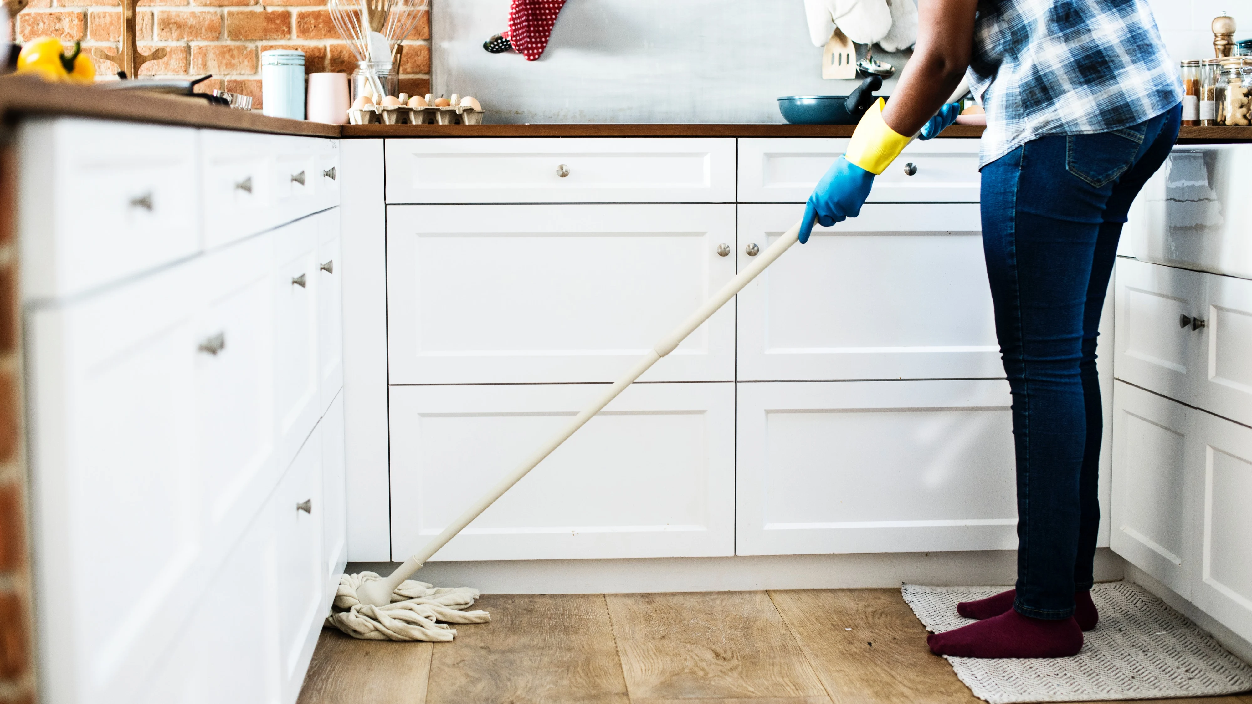 Una mujer friega el suelo de la cocina de su casa Una mujer friega el suelo de la cocina de su casa