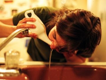 Una mujer lavándose la nariz con una 'Neti Pot', vasija especial para ello