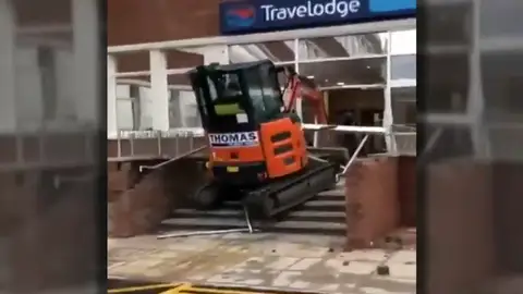 Un trabajador enfurecido estrella su excavadora contra la entrada de un hotel Un trabajador enfurecido estrella su excavadora contra la entrada de un hotel