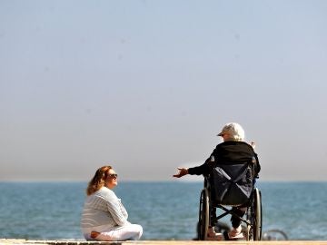 Dos mujeres conversan a orillas del mar mientras disfrutan del sol 
