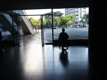 Un hombre mira por la ventana en una oficina sin luz en Caracas, Venezuela. Un hombre mira por la ventana en una oficina sin luz en Caracas, Venezuela.