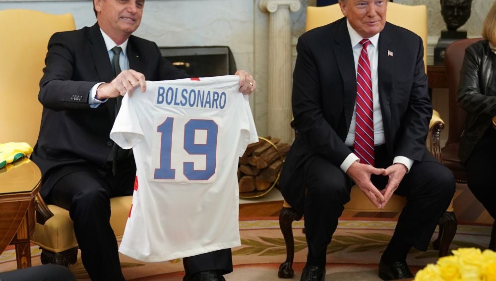 El presidente de EEUU, Donald Trump, recibe una camiseta la selección brasileña durante la reunión con Jair Bolsonaro