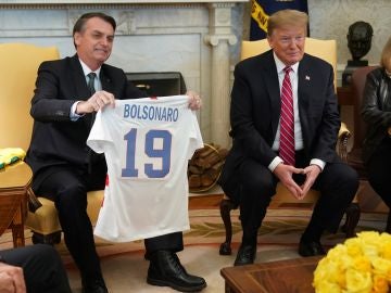 El presidente de EEUU, Donald Trump, recibe una camiseta la selección brasileña durante la reunión con Jair Bolsonaro