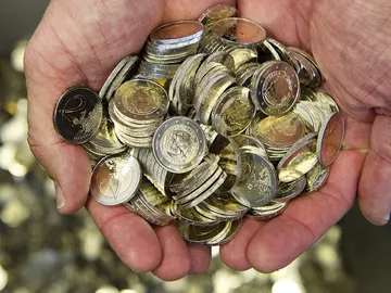 Un hombre sostiene monedas de euro Un hombre sostiene monedas de euro