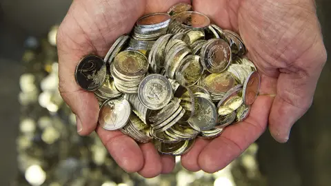 Un hombre sostiene monedas de euro Un hombre sostiene monedas de euro