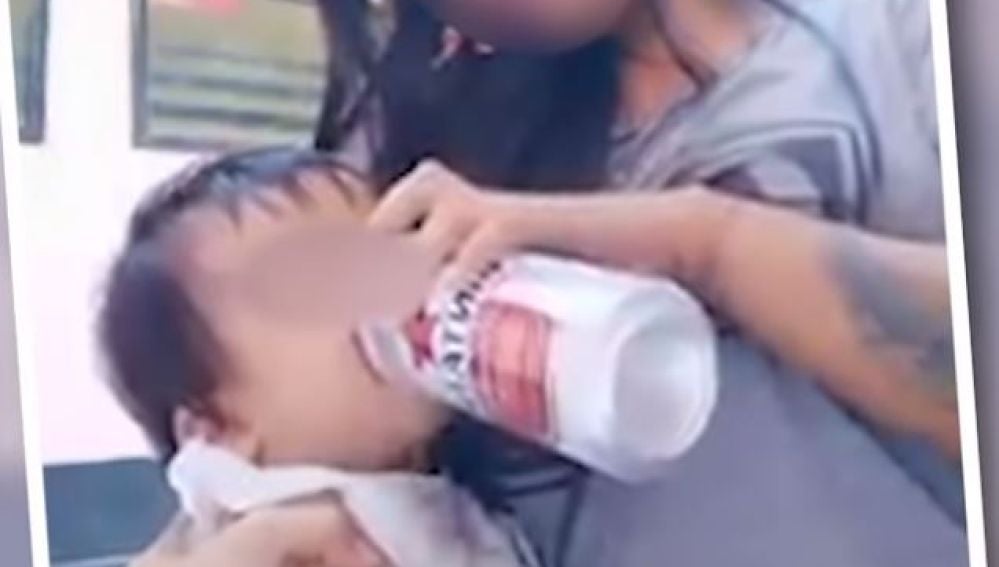 Una madre dándole cerveza a su hijo