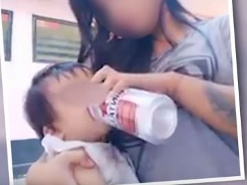 Una madre dándole cerveza a su hijo