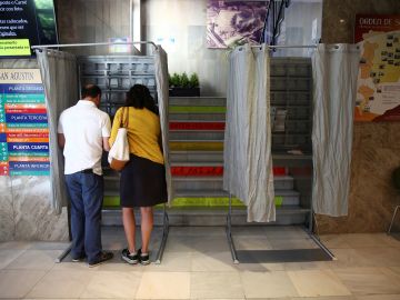 Dos personas eligen sus papeletas para votar en un colegio electoral 
