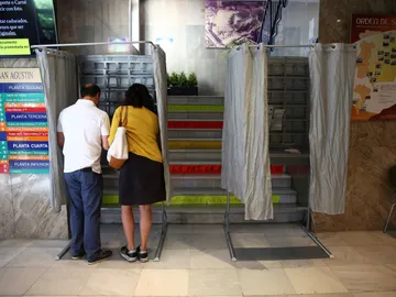 Dos personas eligen sus papeletas para votar en un colegio electoral Dos personas eligen sus papeletas para votar en un colegio electoral