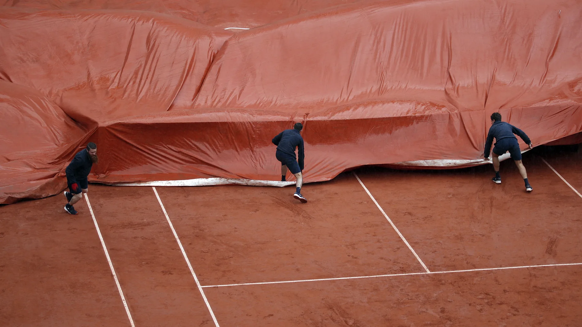 Los operarios de Roland Garros ponen la lona en la Philippe Chatrier Los operarios de Roland Garros ponen la lona en la Philippe Chatrier