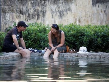  Unos turistas se refrescan en una de las fuentes de Córdoba