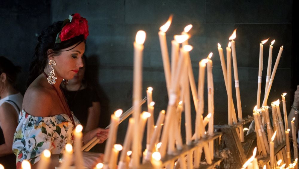 Una rociera coloca una vela en el Santuario de la Virgen del Rocío