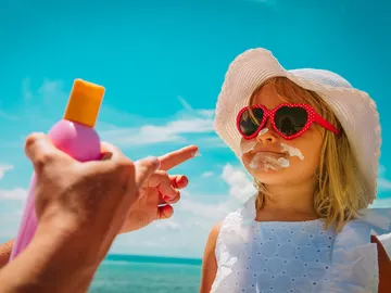 Poniendo crema solar a una niña Poniendo crema solar a una niña
