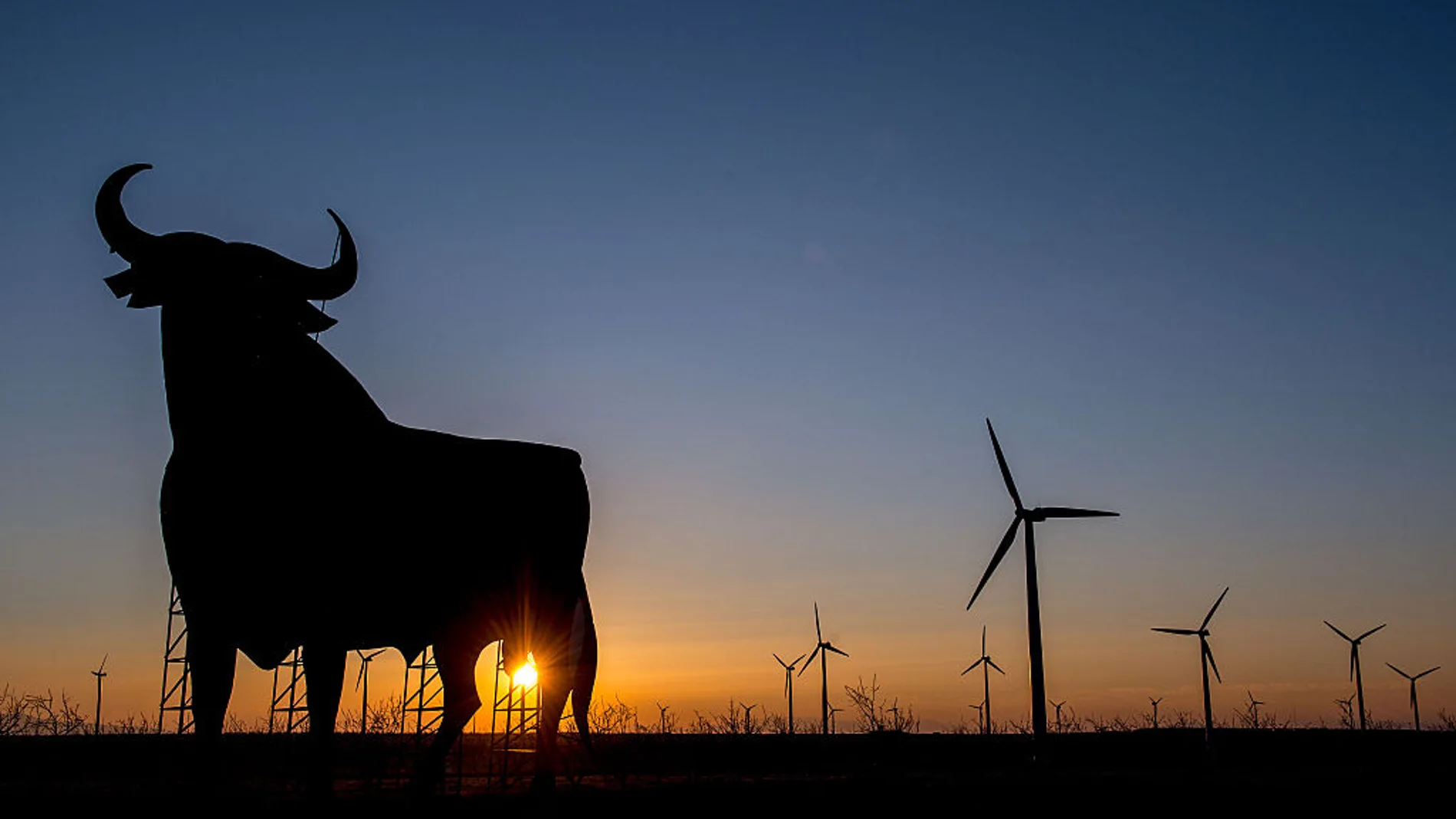 Toro de Osborne en mitad de un campo de molinos eólicos Toro de Osborne en mitad de un campo de molinos eólicos