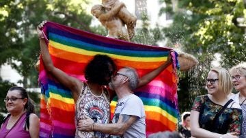 Dos hombres besándose ante la bandera del orgullo gay
