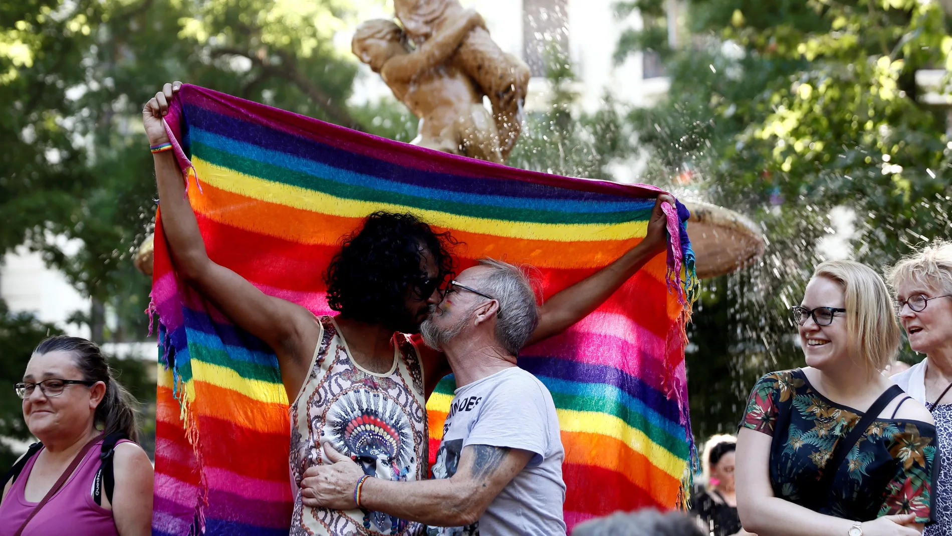 Dos hombres besándose ante la bandera del orgullo gay Dos hombres besándose ante la bandera del orgullo gay