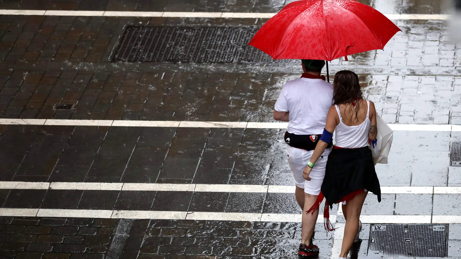 Dos personas se protegen de la lluvia en una de las céntricas calles de Pamplona Dos personas se protegen de la lluvia en una de las céntricas calles de Pamplona