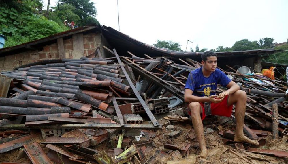 Un joven sobre los escombros de las inundaciones en Lima.